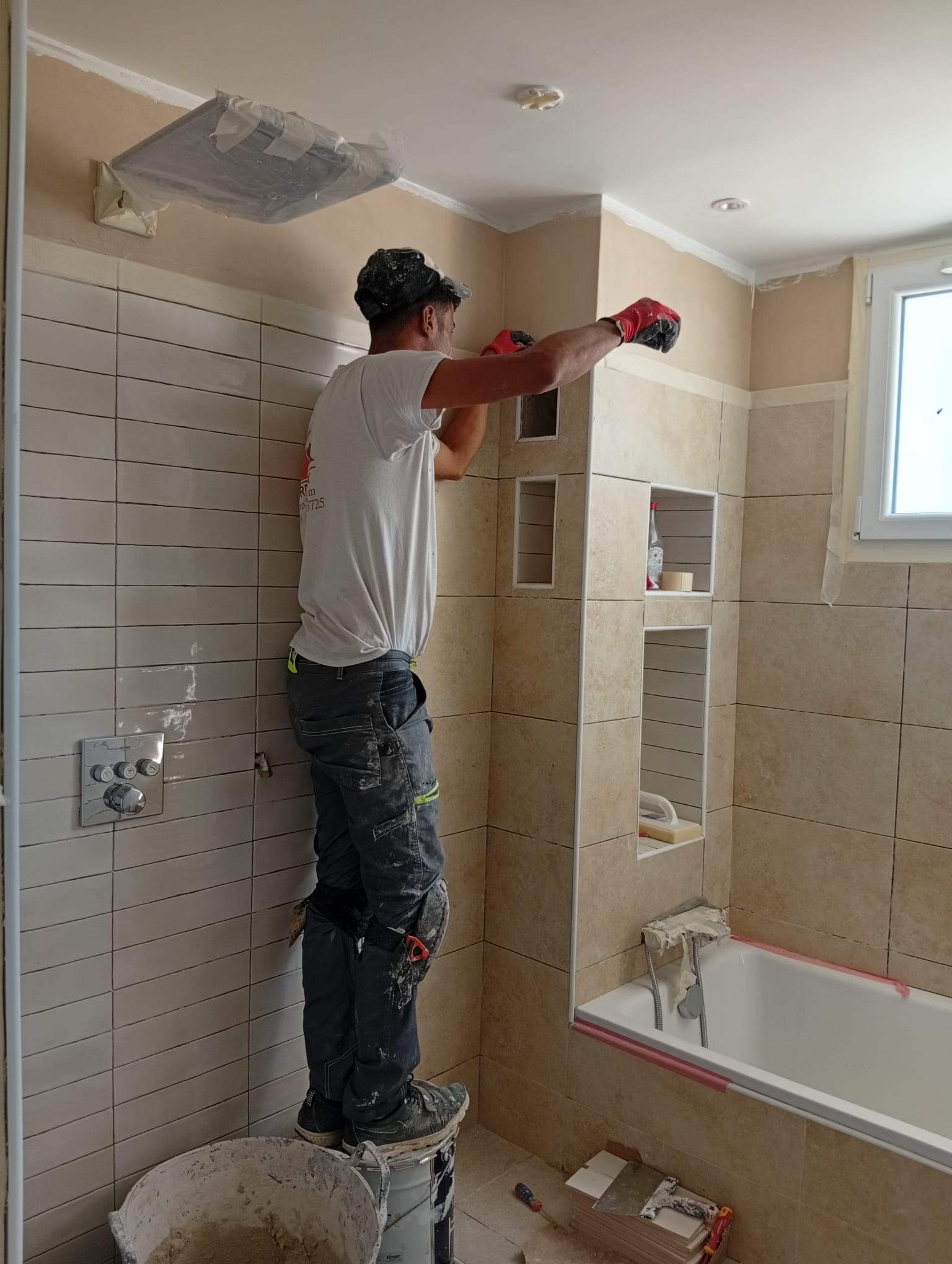 Artisan PRO-REFLEX posant la faïence d'une salle de bain sur un chantier